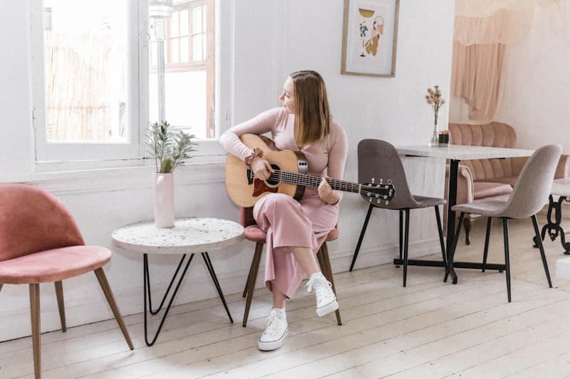 Girl playing guitar in a bright living room