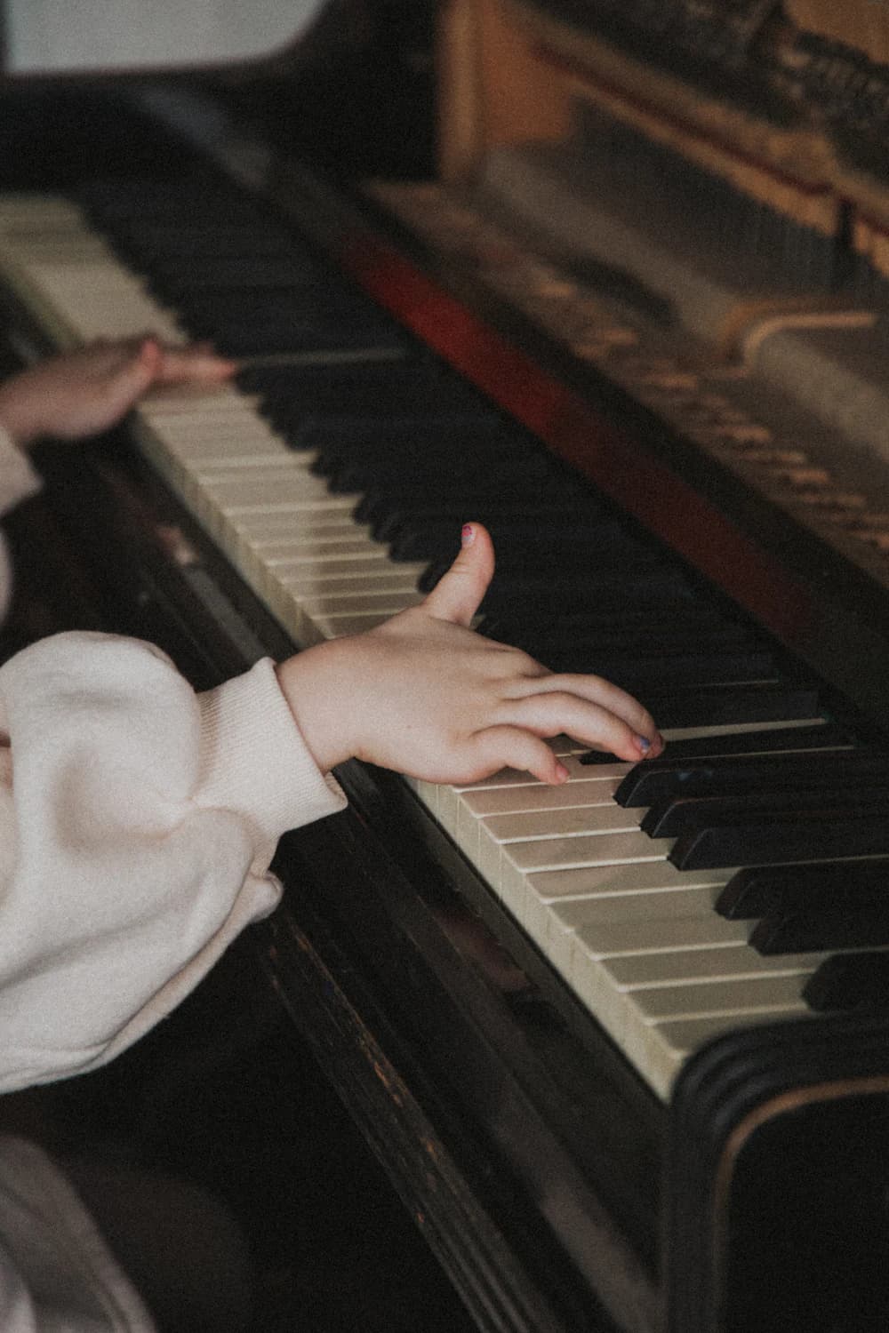 Student's hands resting on piano keys in soft light